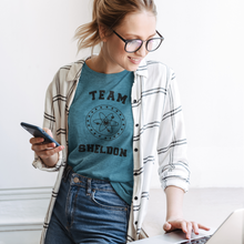 Load image into Gallery viewer, Team-Sheldon-Bazina-T-Shirt-worn-byan-attractive-young-woman-with-messy-hair-working-on-her-laptop