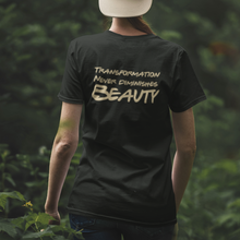 Load image into Gallery viewer, Woman with cap on backwards walking away wearing the "Transformation Never Diminishes Beauty" Black T-Shirt, in a forrest.