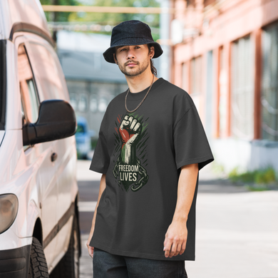 Man wearing a black t-shirt with a graphic design and text, standing outdoors.