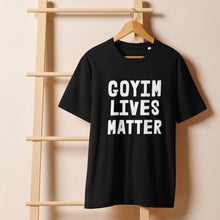 Load image into Gallery viewer, Black t-shirt with 'GOYIM LIVES MATTER' text on a wooden hanger against a beige wall.
